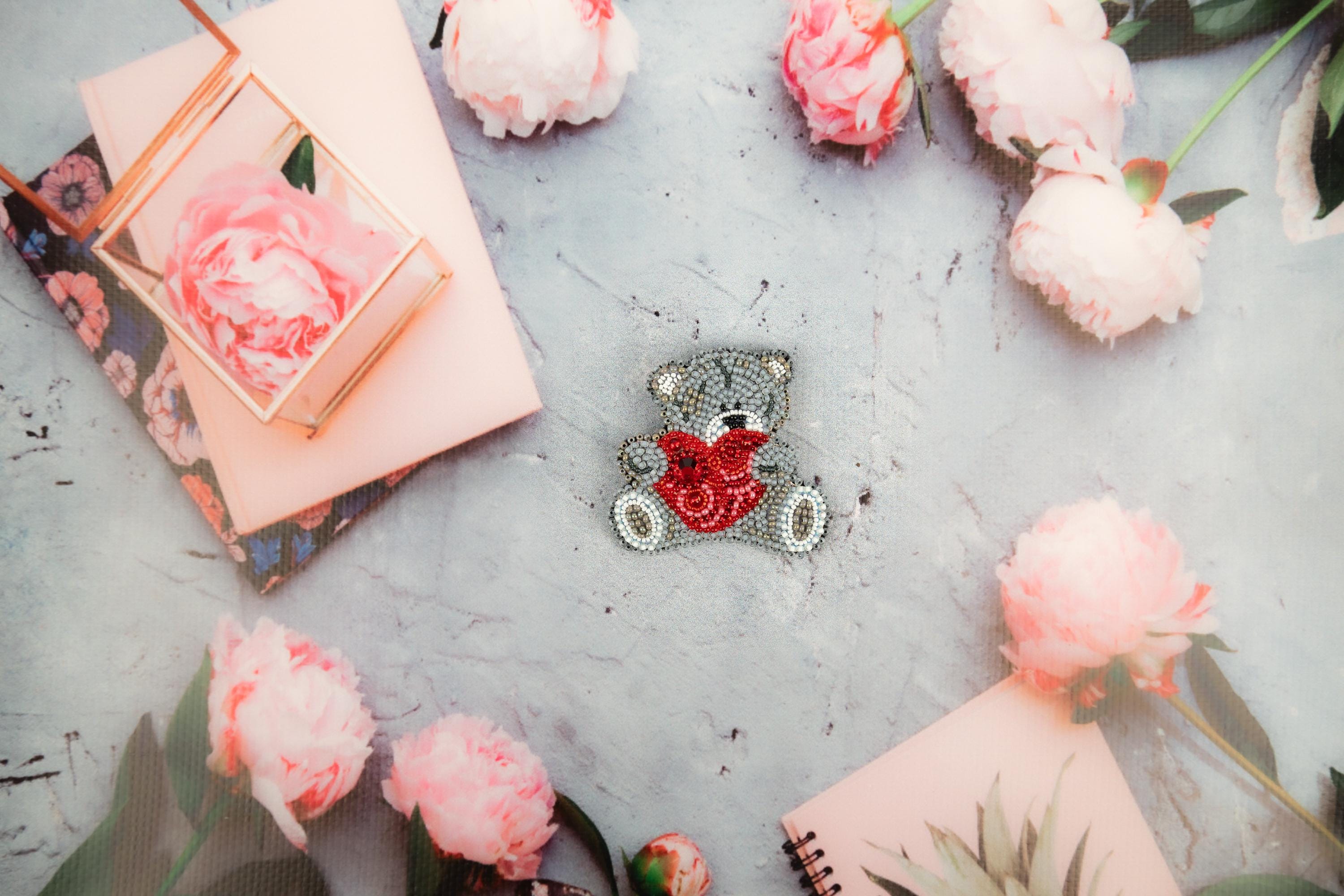 a pin with a heart on it surrounded by flowers